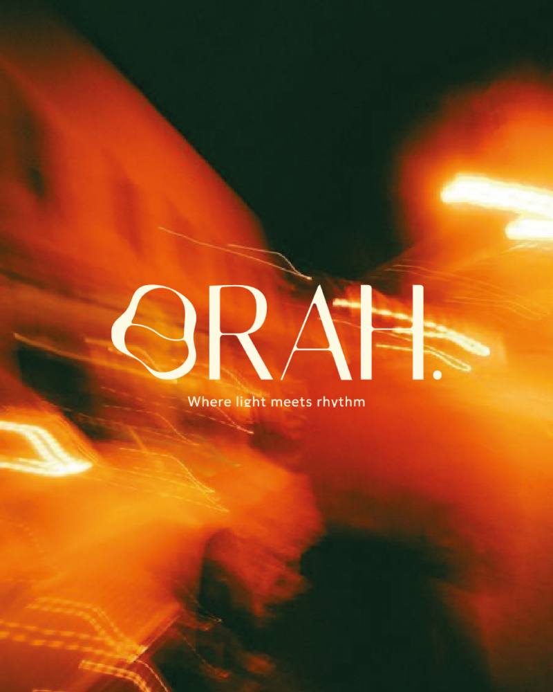 Le logotype ORAH. en clair sur une photo de rue filée en orange, avec la signature « Where light meets rhythm »