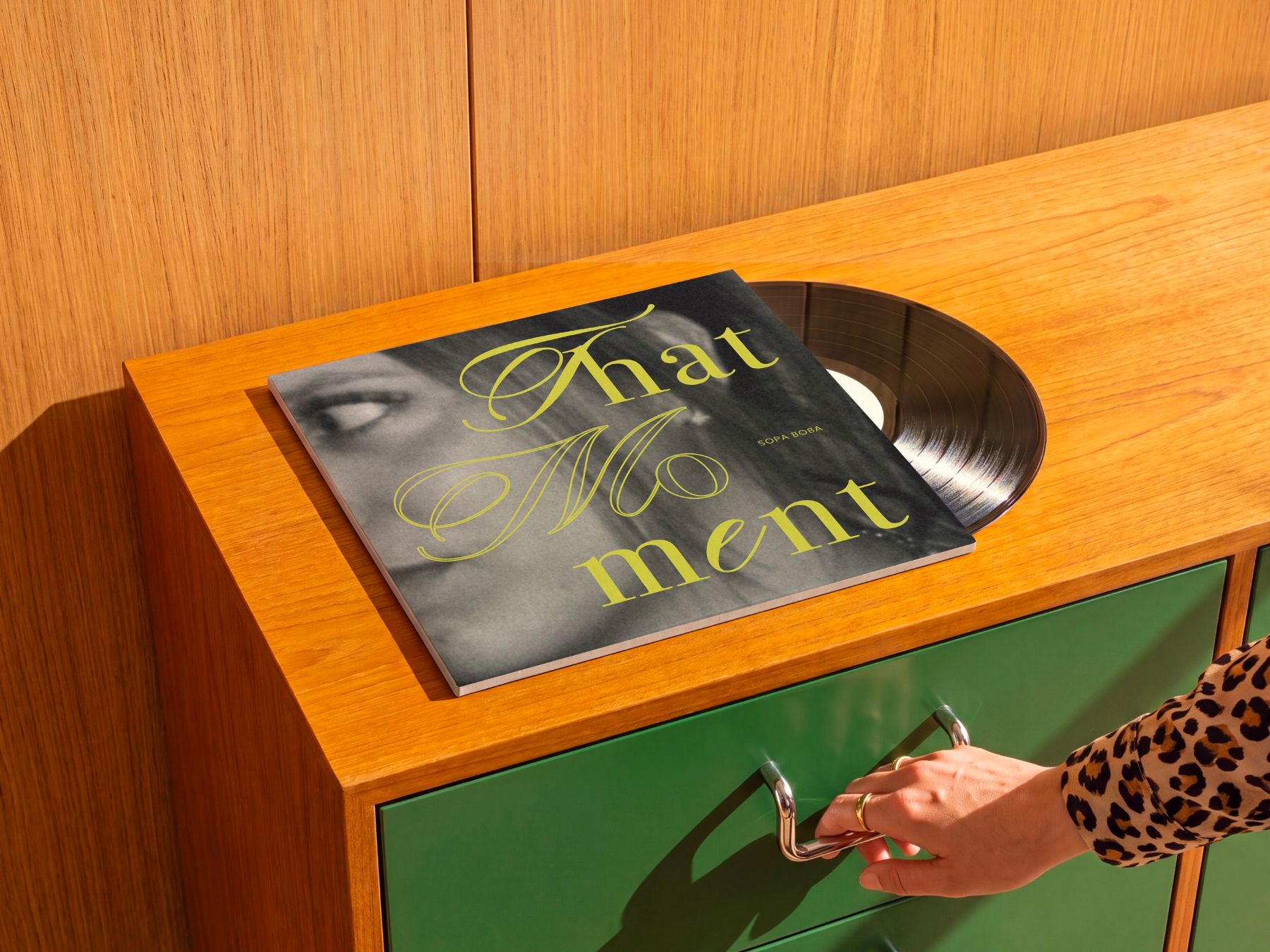 La pochette sur une commode verte, une main sur la poignée du tiroir