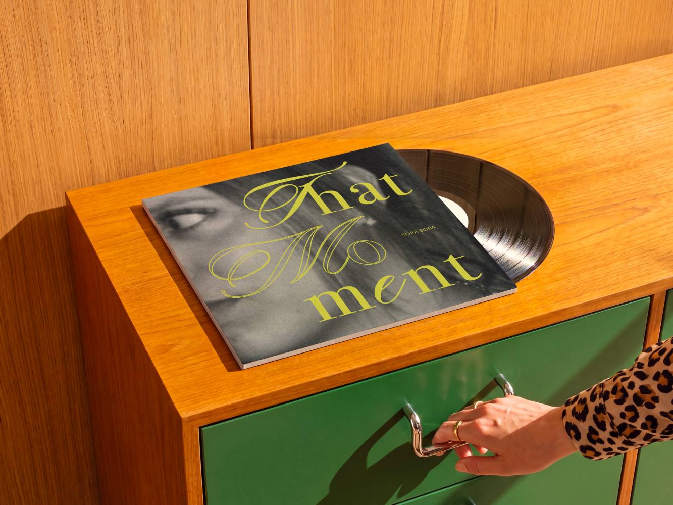 Le disque posé sur un tourne-disque vintage, une main sur le meuble